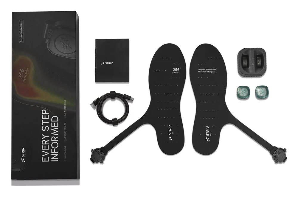 A STRIV research kit: insoles, two sensor pods, a charging dock and a cable